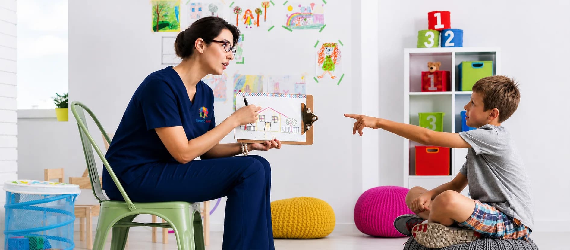 Una terapeuta del centro conversa con un niño mostrándole un dibujo